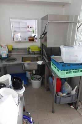 une petite cuisine avec un évier et beaucoup de vaisselle sur le plan de travail