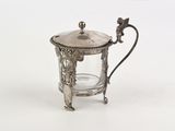 a small silver teapot with a glass in it