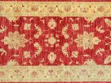 a close up of a red and beige rug on a wooden floor