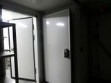 une porte blanche dans une pièce sombre, à côté d'une étagère