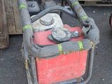 un extincteur rouge et noir posé à côté d'un tas de bois