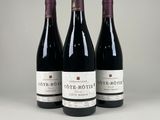 trois bouteilles de vin rouge sont alignées sur une table