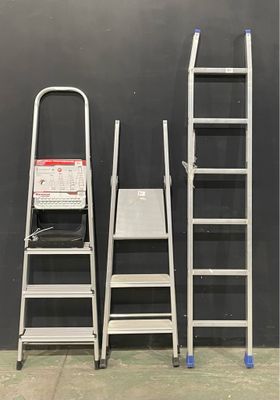 several ladders are lined up against a black wall in a warehouse