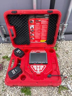 une mallette à outils rouge ouverte posée sur un sol recouvert de gravier