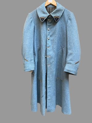 un manteau en laine bleu suspendu à un cintre sur un fond gris