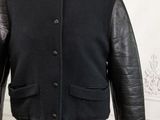 black jacket with leather sleeves on mannequin display in room