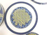 several plates and bowls with blue and yellow designs sit on a table