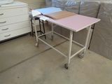 a table with a pink top sitting on a cart in the middle of a room