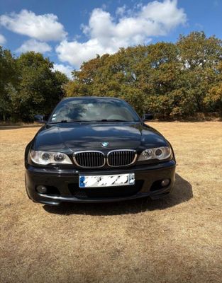 a picture of a black bmw car parked in a field