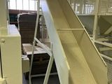 Dans un entrepôt, des cartons sont empilés sur un tapis roulant