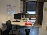 a desk with two computers and a chair in the room