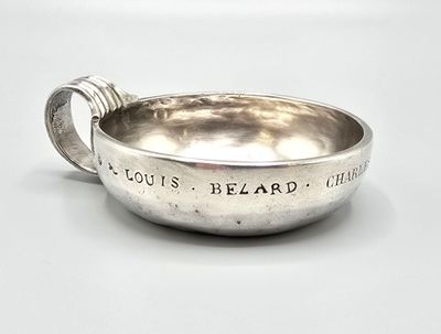 un bol en argent avec une poignée sur une surface blanche