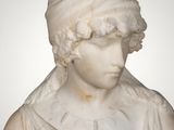 an antique marble bust of a woman wearing a head scarf