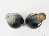 two bottles of wine sitting next to each other on a white surface