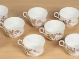 six cups and a saucer on a wooden table