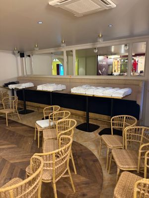 Des tables et des chaises sont disposées dans une salle, avec un bar en arrière-plan.