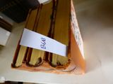 une pile de livres posée sur une étagère, sur laquelle est collée une étiquette en papier