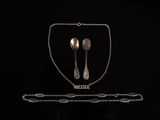 two silver spoons and a chain on a black background