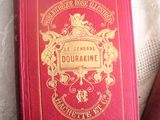 un livre rouge posé sur un lit, à côté d'un autre livre