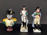 trois figurines représentant des hommes en uniforme militaire, posées sur un fond noir