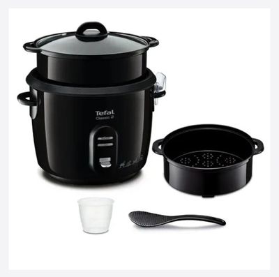 un cuiseur à riz noir, avec un verre et une cuillère à côté