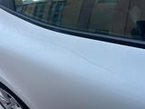 une voiture blanche dont la vitre est fissurée, garée sur le bord de la route
