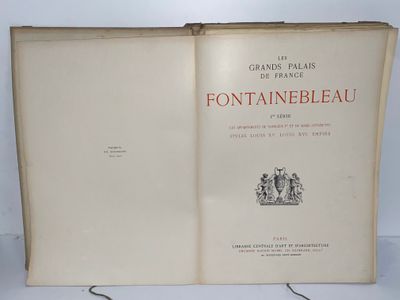 un livre ouvert posé sur une table, à côté d'une lampe