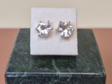 a pair of earrings sitting on top of a marble block