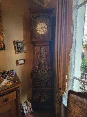 a grandfather clock in the corner of a room next to a window