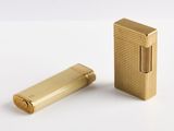 un étui à cigarettes doré et un briquet posés sur une surface blanche