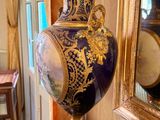 a blue and gold vase sitting on a table in front of a mirror