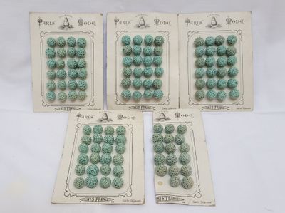 four cards of green beads are on a white surface