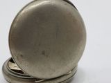 a silver pocket watch sitting on top of a white table