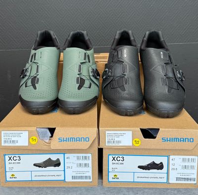 Trois paires de chaussures Shimano sont exposées dans une boîte