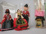 three dolls in a glass case on a table