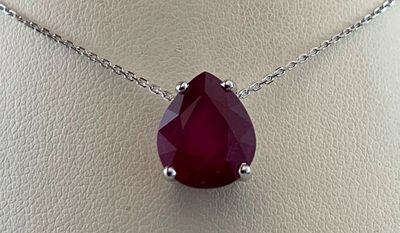 un gros plan d'un collier orné d'une pierre rouge sur un mannequin