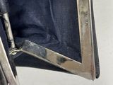 a black purse with a silver handle on a white surface