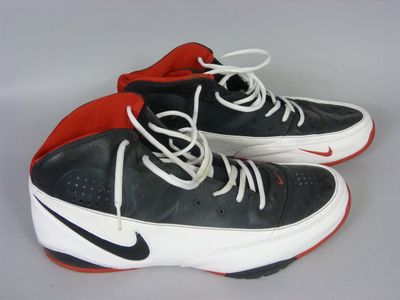 pair of black and white sneakers with red soles on a gray surface