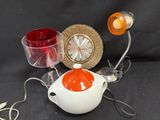 une théière blanche avec un couvercle orange et une tasse rouge posées sur une table