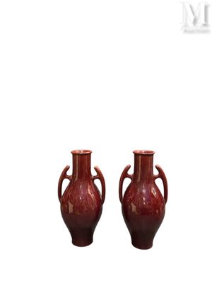 une paire de vases rouges munis d'anses de chaque côté d'un fond blanc