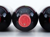 three bottles of wine are lined up on a white surface