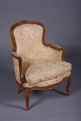 une vieille chaise avec une assise rembourrée beige et un cadre en bois