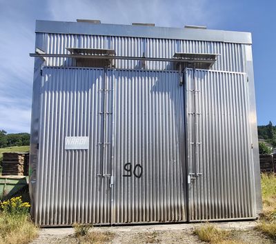 une photo d'une cabane de toilettes en métal au milieu d'un champ