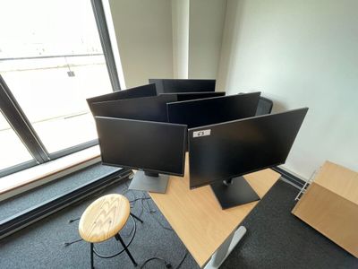 trois écrans d'ordinateur posés sur un bureau dans un bureau