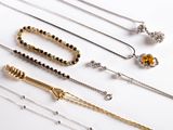 various types of necklaces and bracelets laid out on a white surface