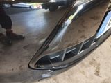 a close up of a car ' s front bumper with a person standing in the background