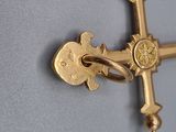 a gold cross hanging on the wall with a key in it