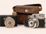 three old cameras sitting next to each other on a white surface