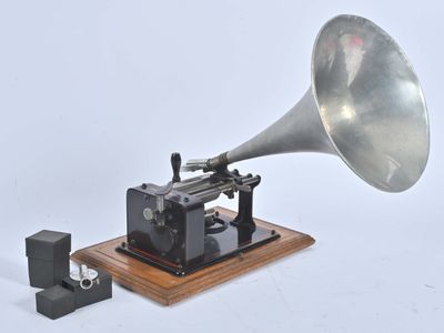 un gramophone argenté et noir posé sur un socle en bois