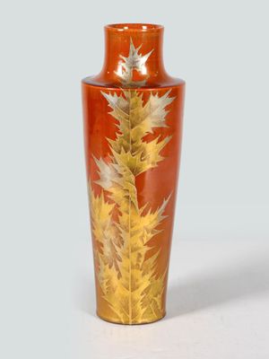 a red vase with a gold leaf design on it